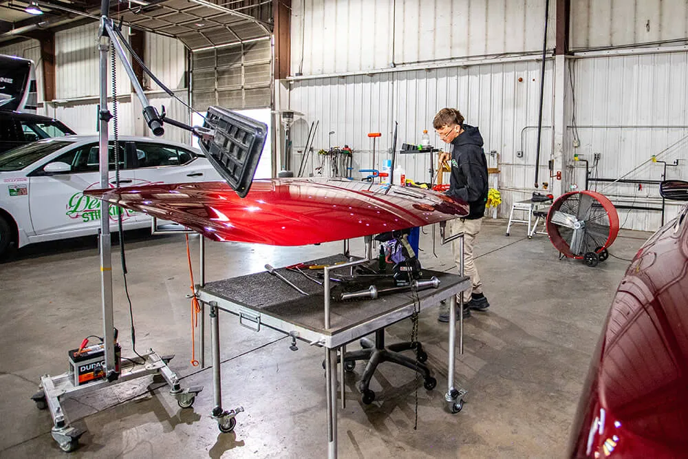 Team member repairing vehicle hood