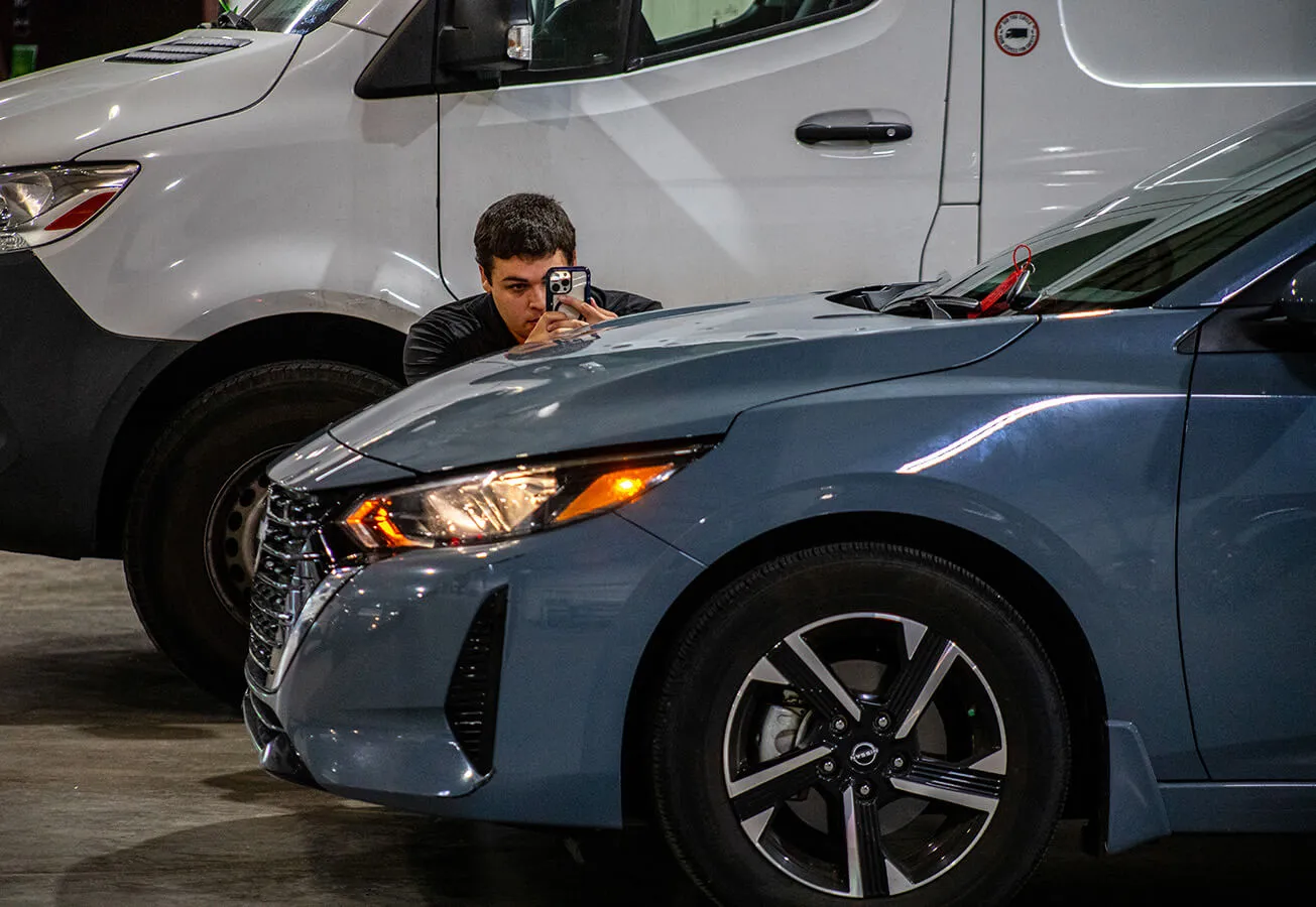 Staff taking photos of hail damage on vehicle