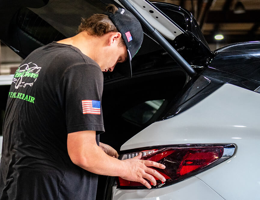 A Dent Source LLC employee installing a rear headlight. 